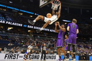 Orlando, FL - March 18: San Diego State's Lamont Butler dunks over Furman's Alex Williams during the second round of the NCAA Tournament in Orlando on Saturday, March 18, 2023.. (K.C. Alfred / The San Diego Union-Tribune)