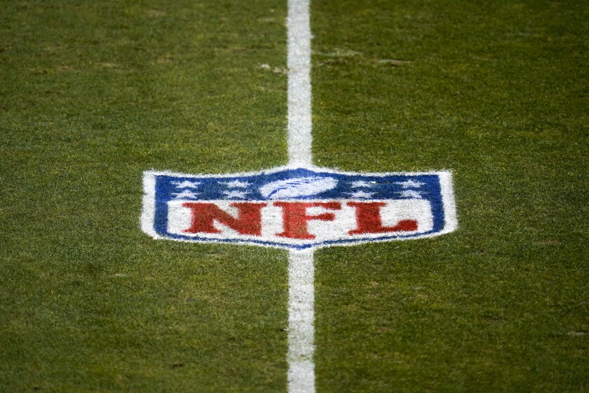 File-This Jan. 3, 2021, file photo shows the NFL logo on the field before a game between the Denver Broncos and the Las Vegas Raiders in Denver. The NFL and NFL Players Association have updated COVID-19 protocols to loosen restrictions for fully vaccinated players and to encourage others to get the vaccine. Unvaccinated players must continue to get daily testing, wear masks and practice physical distancing. They won’t be allowed to eat meals with teammates, can’t participate in media or marketing activities while traveling, aren’t permitted to use the sauna or steam room and may not leave the team hotel or interact with people outside the team while traveling. (AP Photo/Jack Dempsey, File)