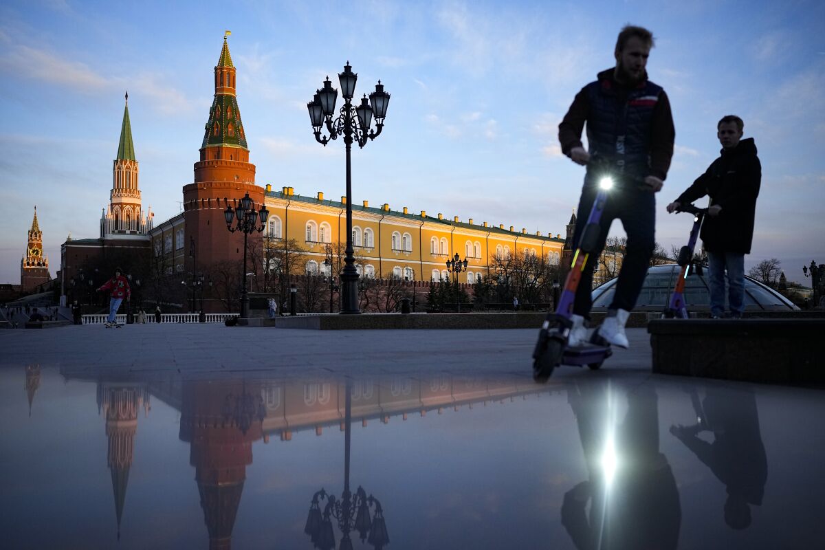 FILE - Youth ride scooters in Manezhnaya Square near Red Square and the Kremlin after sunset in Moscow, Russia, on April 20, 2022. Russia staved off a default on its debt Friday, April 29, 2022, by making a last-minute payment using its precious dollar reserves sitting outside the country, U.S. Treasury officials said. (AP Photo/Alexander Zemlianichenko, File)