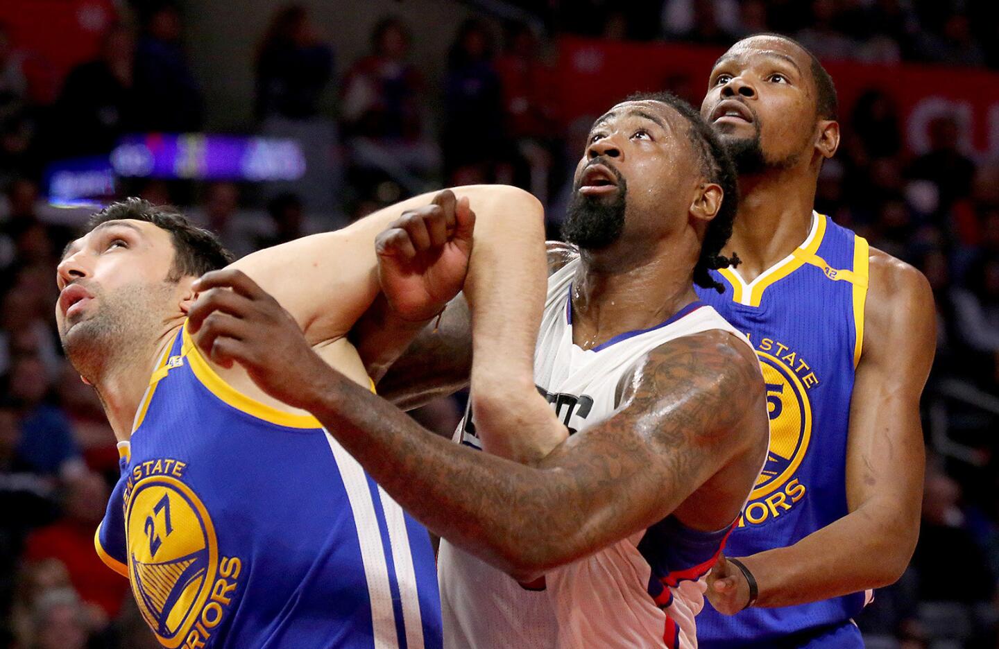 Clippers center DeAndre Jordan fights for rebounding position against Warriors center Zaza Pachulia, left, and forward Kevin Durant during the second quarter Wednesday.