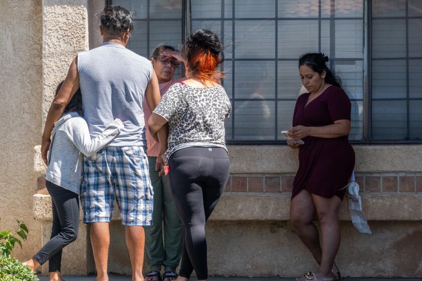 PALMDALE, CA - SEPTEMBER 18: A woman described as the mother of the suspect, (left facing camera), and others stand outside the house in the 37600 block of Barrinson Street in Palmdale, CA on Monday, Sept. 18, 2023 where the shooting suspect was arrested. During a press conference at the Palmdale Sheriff's Station, Los Angeles County Sheriff Robert Luna announces the arrest of a suspect in the shooting death of Dep. Ryan Clinkunbroomer. (Myung J. Chun / Los Angeles Times)