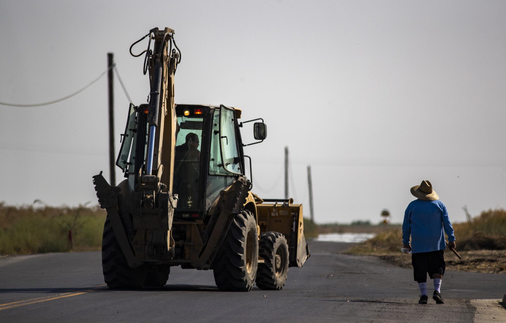 A pedestrian shares the road with a tractor in Stratford.