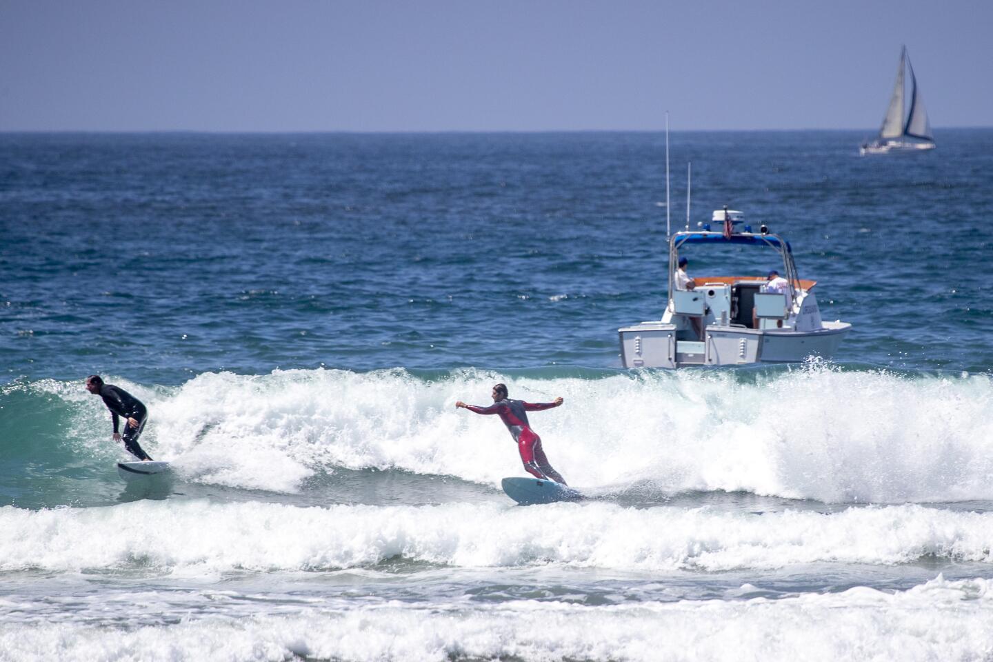 Lifeguards patrol with a boat as surfers ride waves