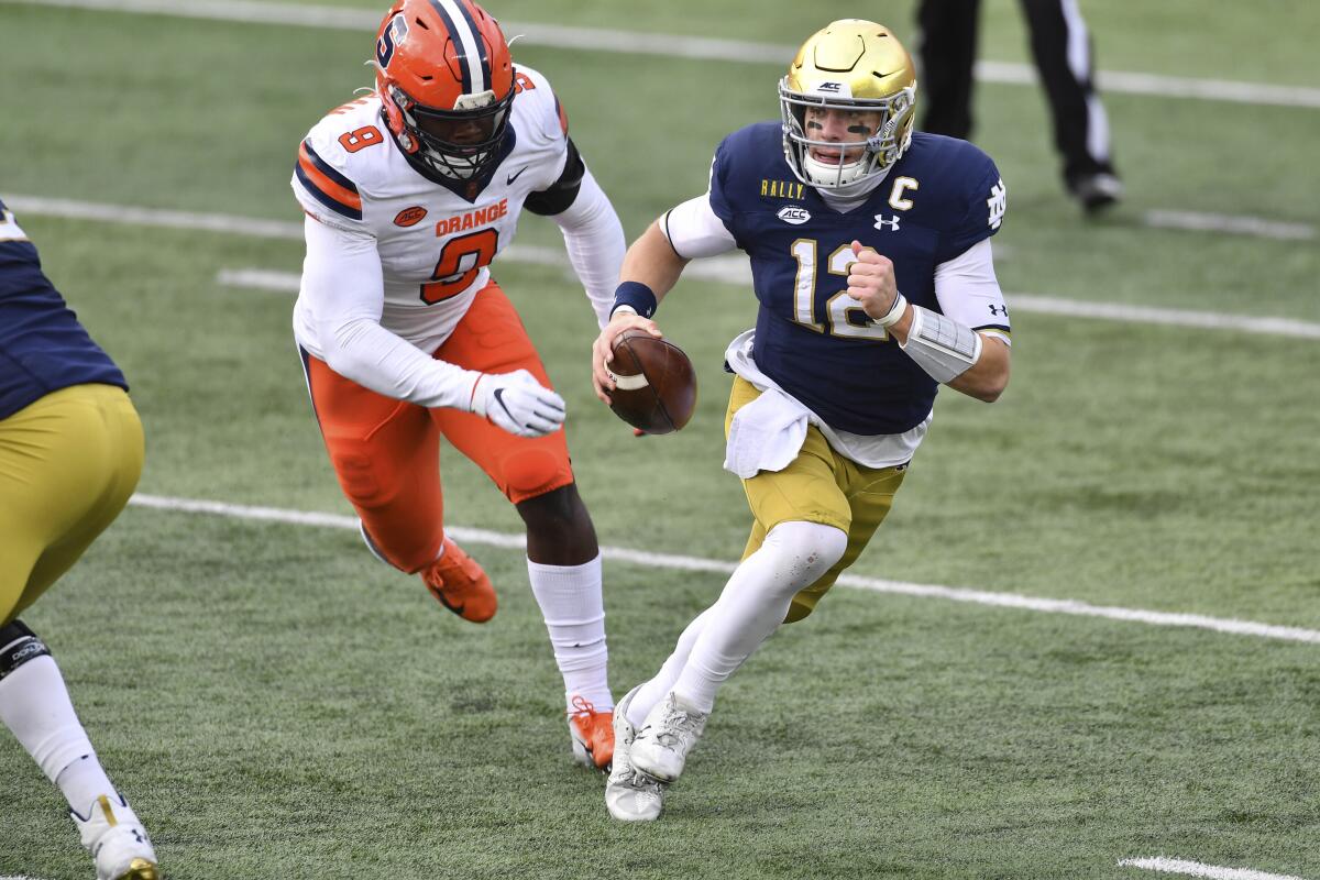 Notre Dame quarterback Ian Book runs with Syracuse defensive lineman Jonathan Kingsley in pursuit.