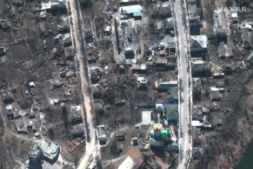 FILE - This satellite image provided by Maxar Technologies shows damaged buildings during fighting in Izium, Ukraine, on March 24, 2022. On Friday, Sept. 30, The Associated Press reported on stories circulating online incorrectly claiming that Russian forces did not kill a Ukrainian family whose graves were pictured in a wooded area among scores of others. (Maxar Technologies via AP)