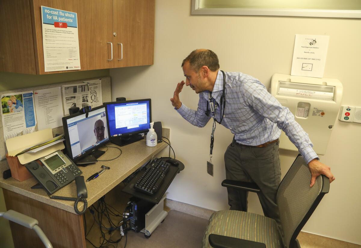 Dr. Nilesh Shah, at the VA Sorrento Valley Clinic in San Diego, waves goodbye to a patient after a video appointment.