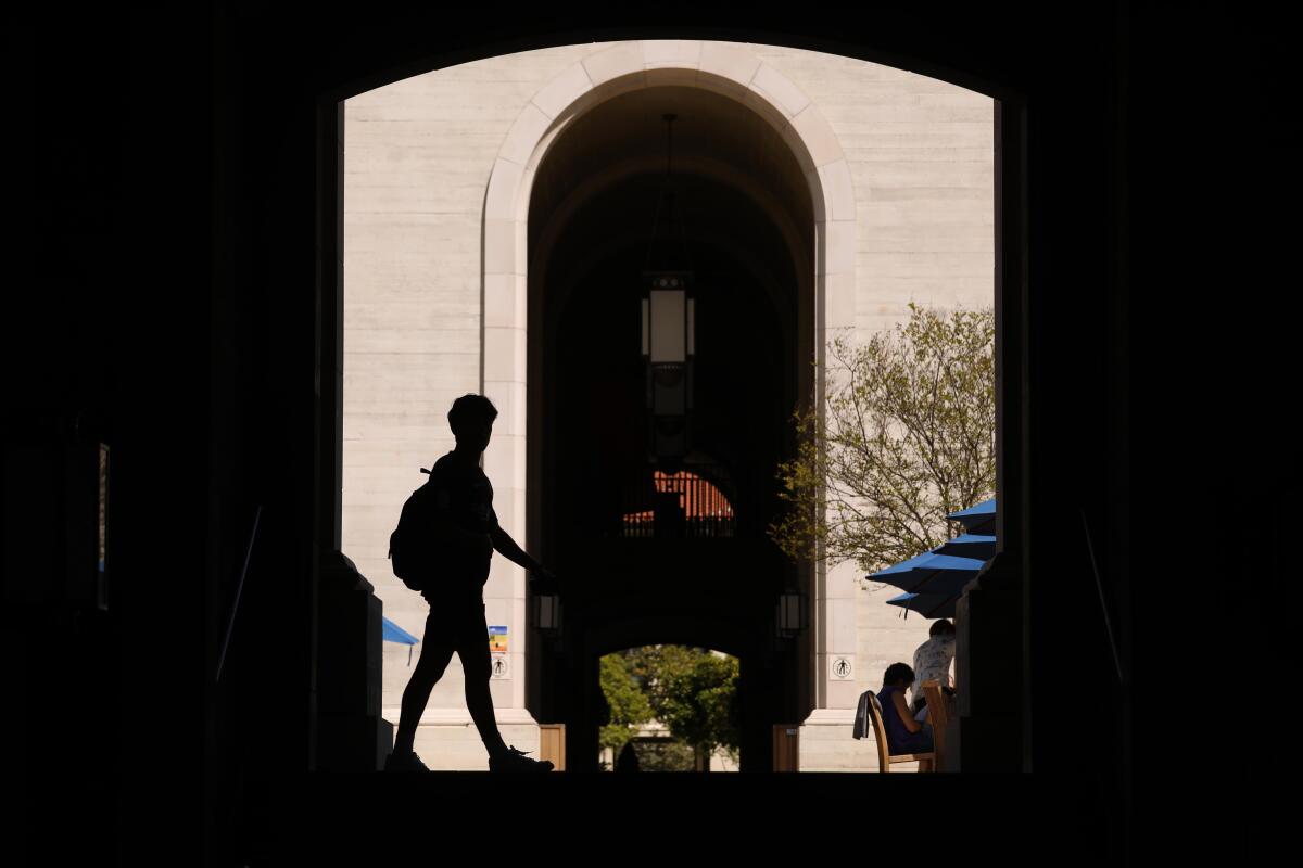 Silhouette of student passing outside doorway on college campus