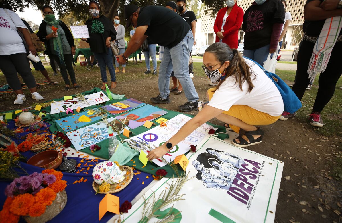 A woman places a card on an altar set up on the ground at a domestic workers protest at a park