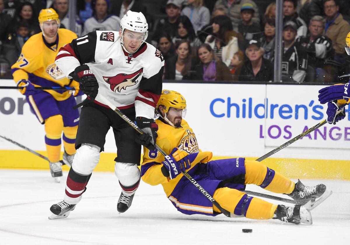 Kings defenseman Drew Doughty, right, grabs the stick of Coyotes center Martin Hanzal as Doughty falls to the ice during the first period>