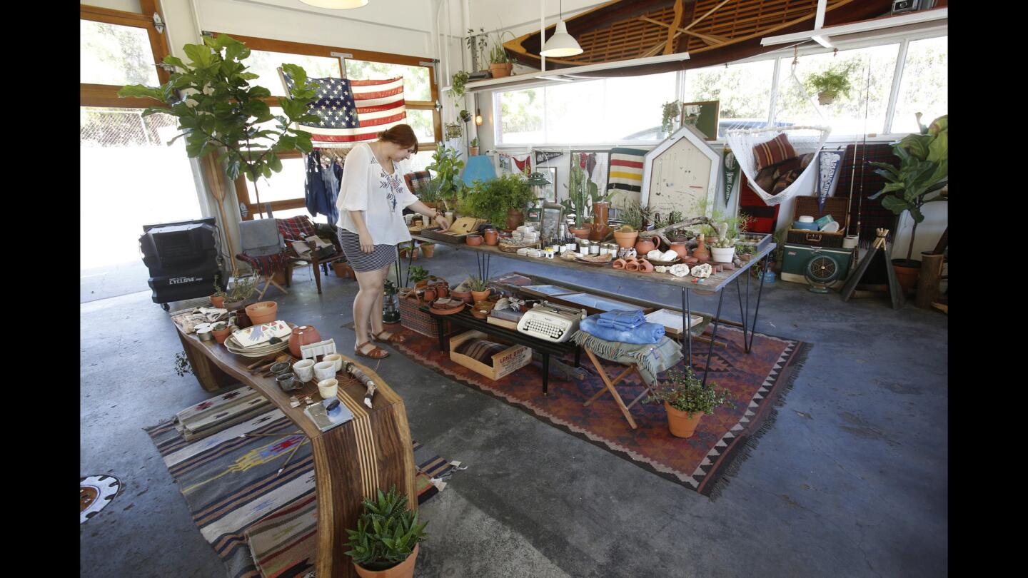 At the west end of Ojai, Michael and Rachel Graves adapted a 1959 gas station into their boutique and custom framing shop, Summer Camp. Rachel, shown here, arranges a table filled with pottery in the former garage.