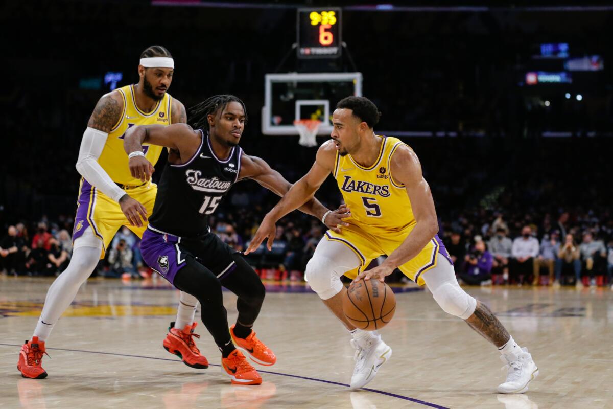 Lakers guard Talen Horton-Tucker drives against Kings guard Davion Mitchell as Carmelo Anthony tries to set a screen.
