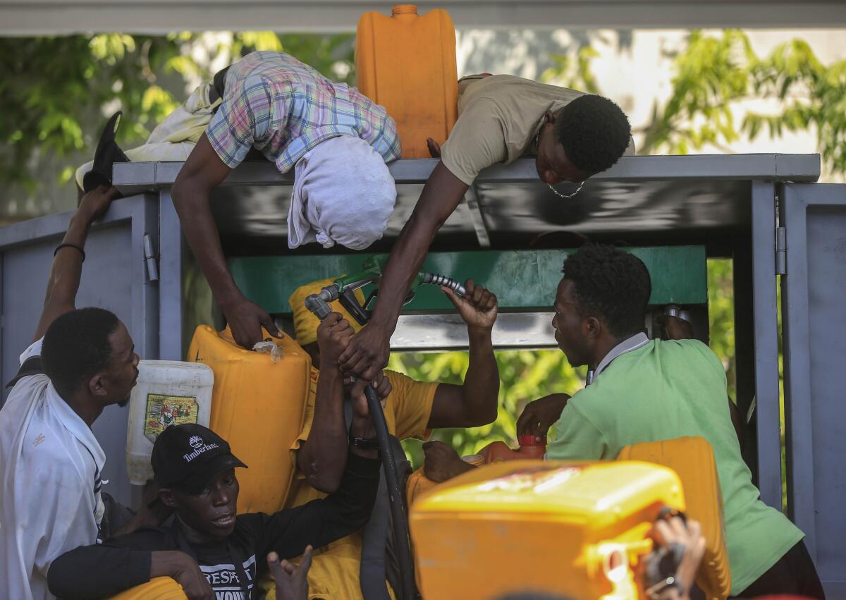 People carrying plastic tanks crowd around a gas pump in Haiti