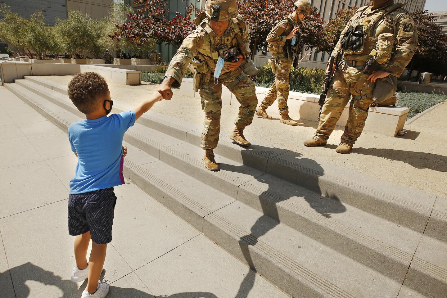 A boy fist-bumps a National Guardsman at LAPD headquarters.