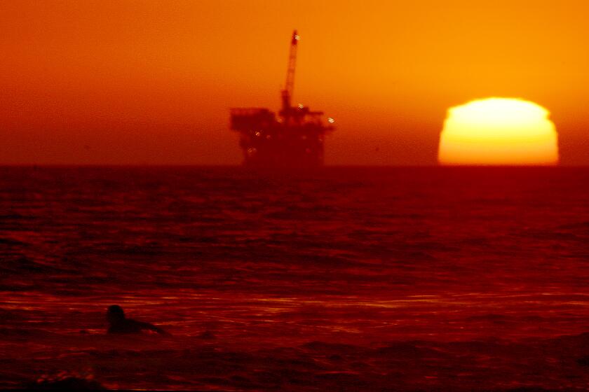 HUNTINGTON BEACH, CALIF. - SEP. 5, 2022. A surfer paddles out as the sun sets at Huntington Beach on Monday, Sep. 5, 2022. (Luis Sinco / Los Angeles Times)
