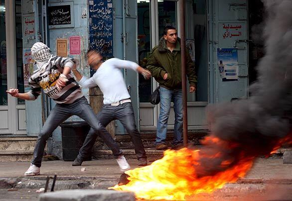Palestinian youths hurl stones at Israeli soldiers during clashes at a rally marking the fourth anniversary of the death of the late Palestinian leader Yasser Arafat in the West Bank city of Hebron.