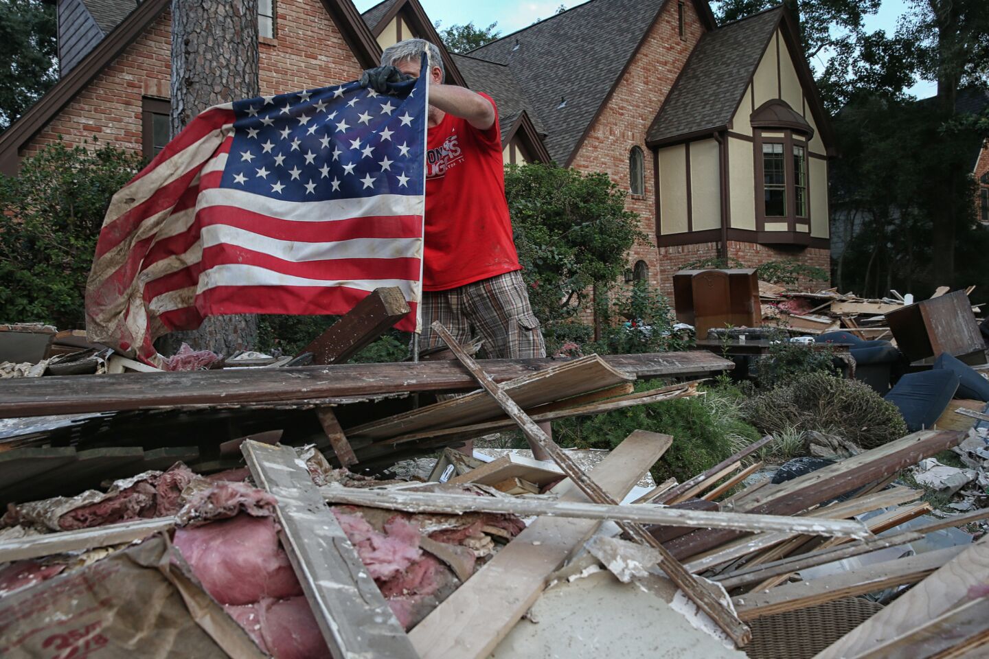 University of Houston law professor Johnny Buckles props up an American flag on the debris pile from his flood-damaged home in the Kingwood area of north Houston.