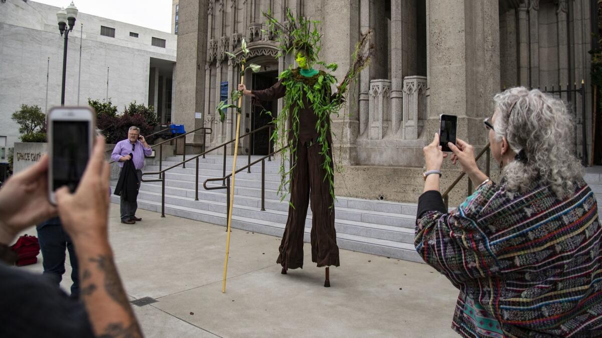 A woman on stilts dressed as a tree captures people's attention outside Grace Cathedral before the Wondering and Commitment ceremony to kick off the Global Climate Action Summit in San Francisco.