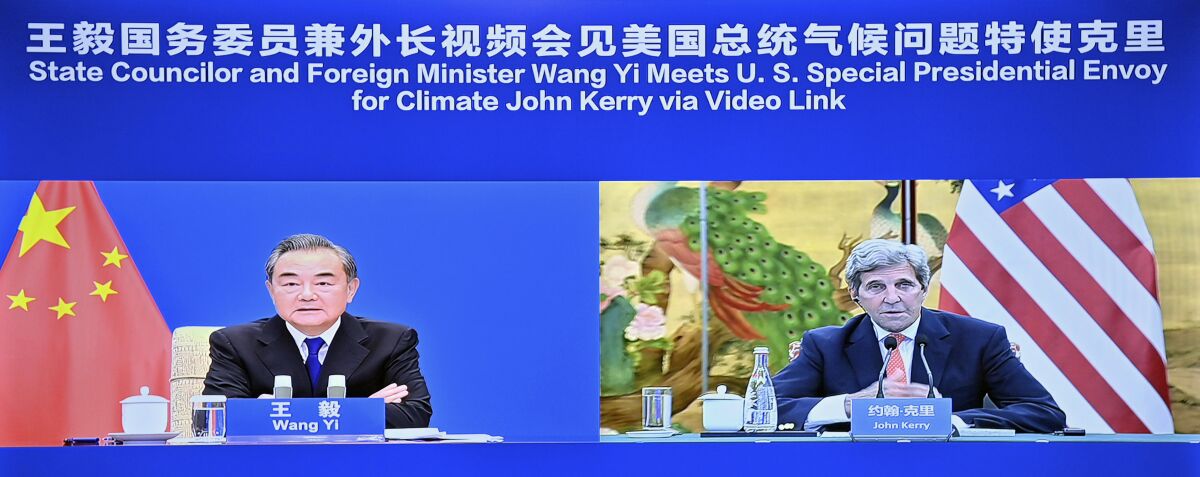 In this photo released by China's Xinhua News Agency, Chinese Foreign Minister Wang Yi, left, and U.S. Special Presidential Envoy for Climate John Kerry meet via video link in China, Wednesday, Sept. 1, 2021. Wang warned Kerry on Wednesday that deteriorating U.S.-China relations could undermine cooperation between the two on climate change. (Yue Yuewei/Xinhua via AP)