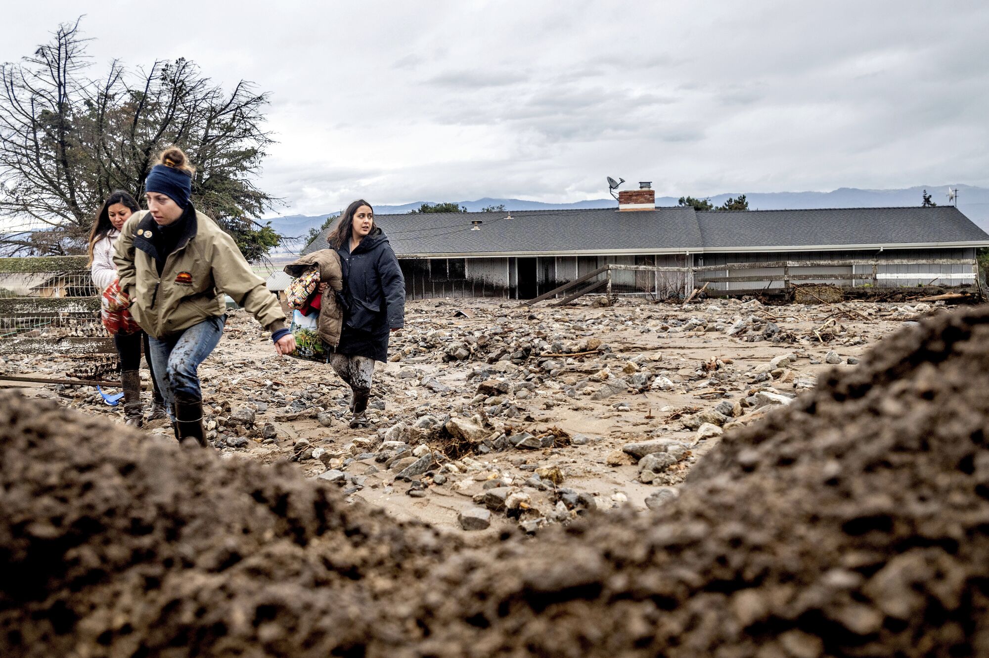 Hana Mohsin, right, carries belongings from a neighbor's home that was damaged in a mudslide on Wednesday in Salinas.