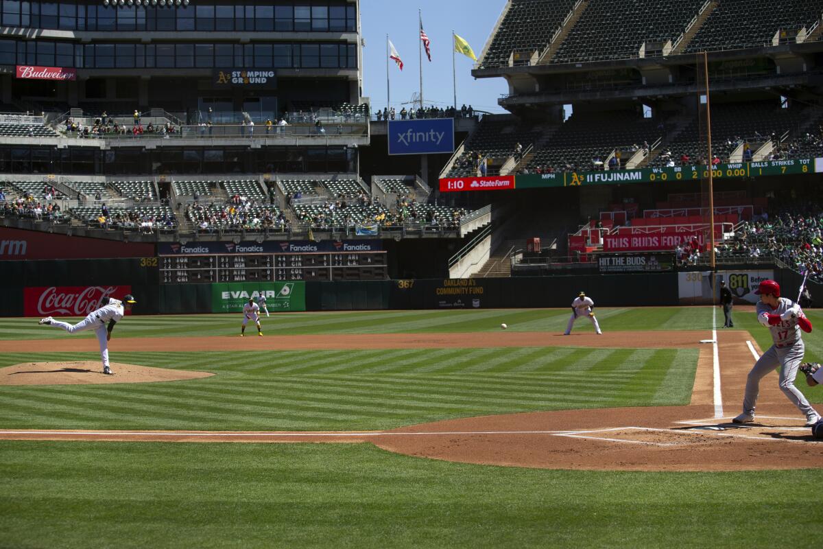 Oakland Athletics starting pitcher Shintaro Fujinami, left, delivers to Angels designated hitter Shohei Ohtani.