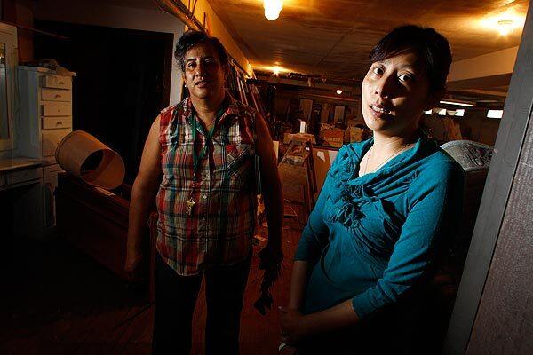 Building manager Gloria Gomez, left, and tenant Yiming Xing were checking the contents of three trunks in the storage room of a MacArthur Park apartment building when they found the remains of two infants. Behind them is the basement where the remains were found. See full story