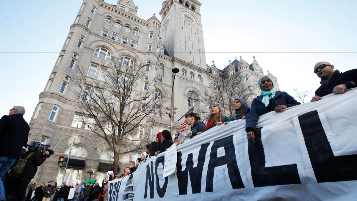 Protesters march along Pennsylvania Avenue in front of the Trump International Hotel in Washington, D.C., on Feb. 4, during a rally protesting President Trump's immigration policies. Hotwire and Priceline are catching heat for booking Trump hotels.