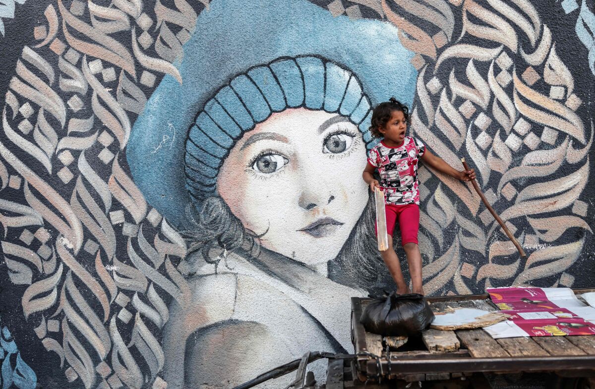 A Palestinian girl stands on donkey cart next to wall painting at a UN school where people are taking shelter in Gaza city.