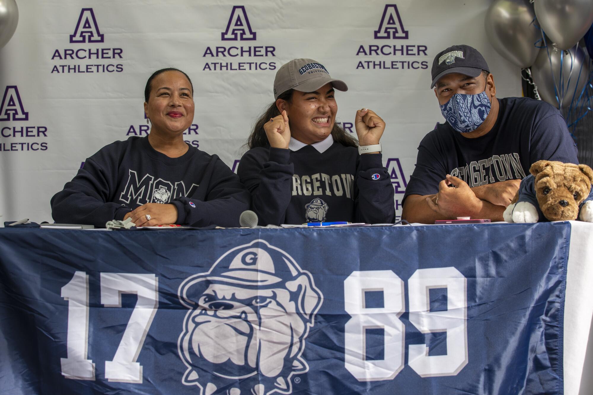 Vaughan Anoa'i is flanked by mother Tiffany Smith-Anoa'i and father Reno Anoa'i at letter-of-intent signing.