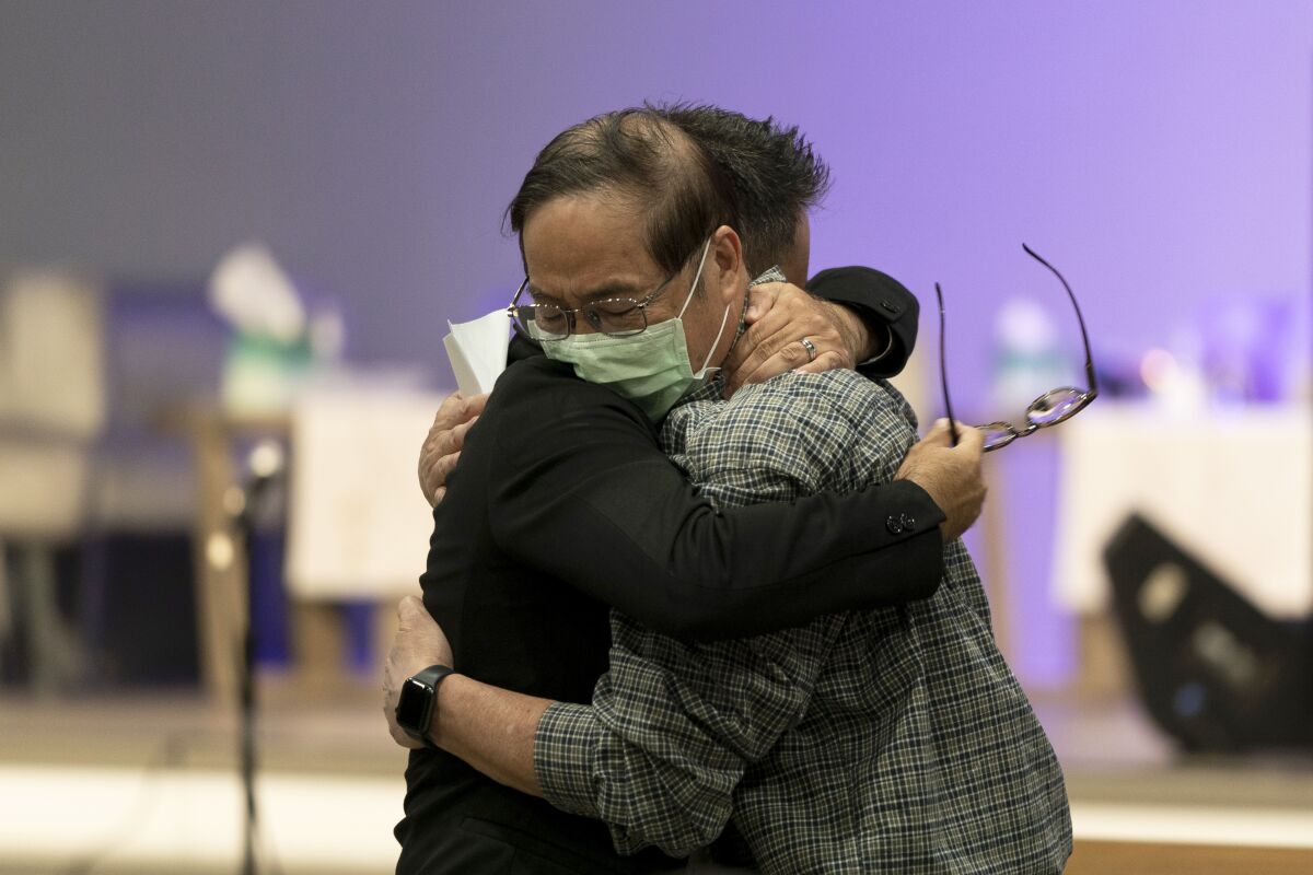 Jason Aguilar, left, a senior pastor at Arise Church, comforts Billy Chang, a 67-year-old Taiwanese pastor who survived Sunday's shooting at Geneva Presbyterian Church, during a prayer vigil in Irvine, Calif., Monday, May 16, 2022. Authorities say a Chinese-born gunman was motivated by hatred against Taiwan when he chained shut the doors of the church and hid firebombs before opening fire on a gathering of mainly of elderly Taiwanese parishioners. (AP Photo/Jae C. Hong)
