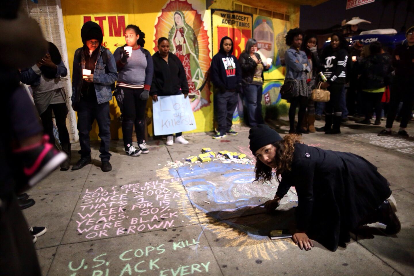 A demonstrator draws a portrait of Ezell Ford near his memorial at 65th Street and Broadway.