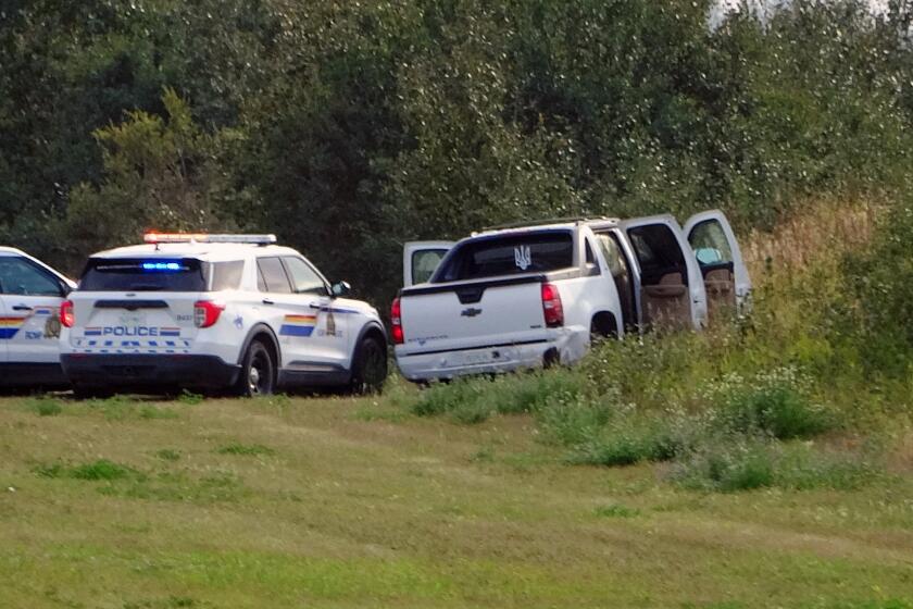 Police and investigators are seen at the side of the road outside Rosthern, Saskatchewan on Wednesday, Sept. 7, 2022. Canadian police arrested the second suspect in the stabbing deaths of 10 people in the province of Saskatchewan on Wednesday after a three-day manhunt during which they had found the body of his brother. (Kelly Geraldine Malone/The Canadian Press via AP)
