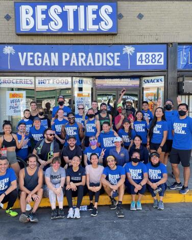 Besties Run Club members pose for a group photo outside the store under a sign that says Vegan Paradise