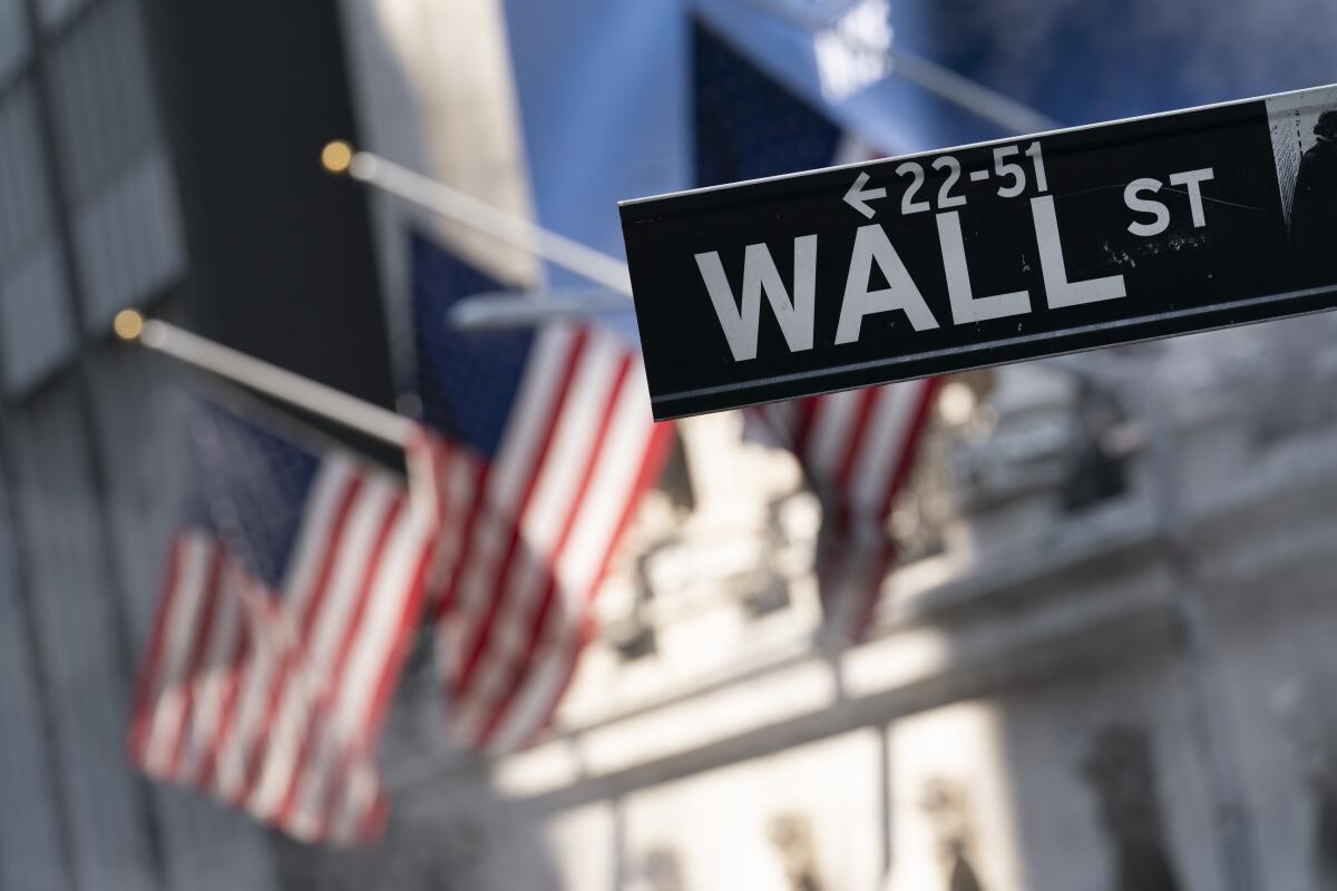 A Wall Street sign and American flags are in front of the New York Stock Exchange. 