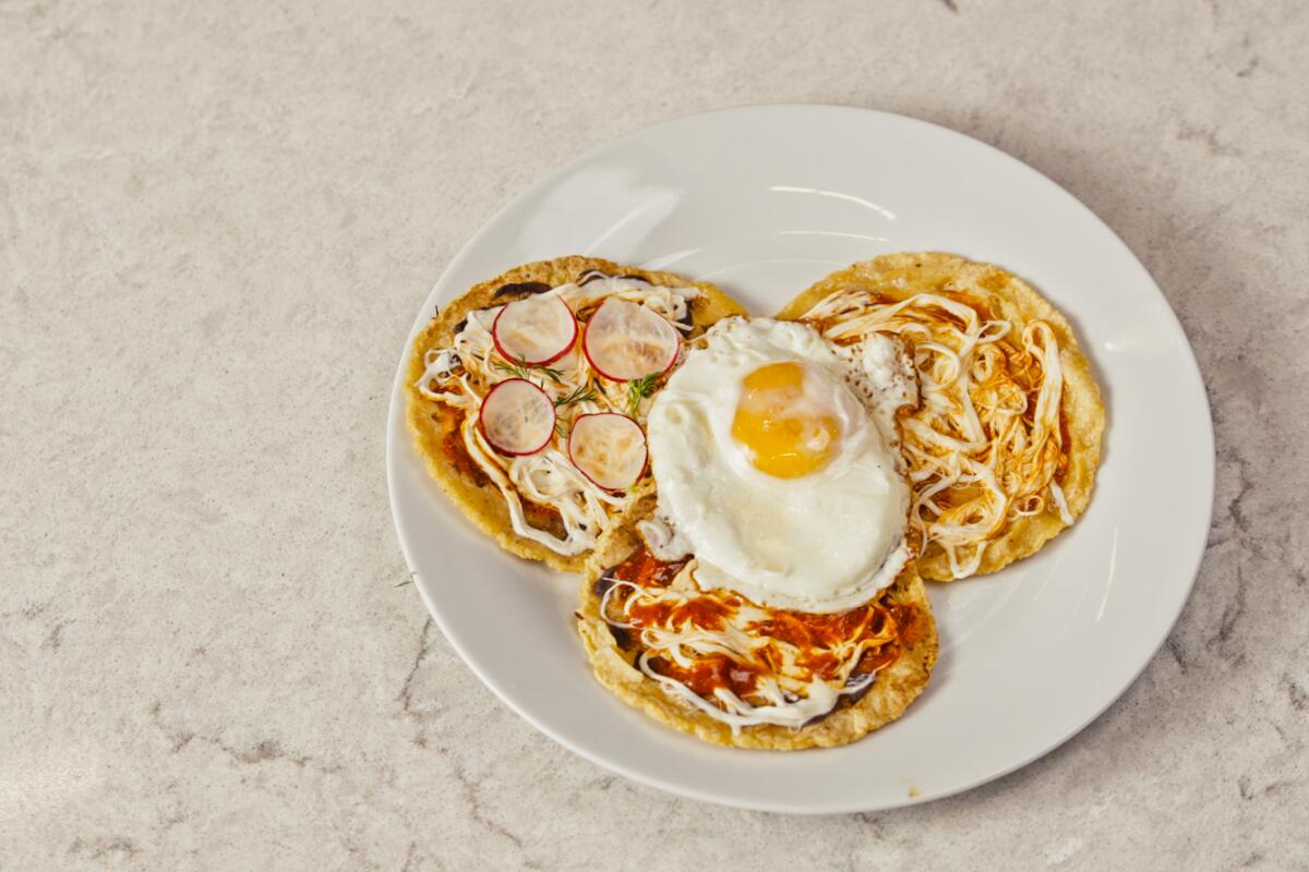 Three round yellow corn cakes with toppings and a fried egg on top