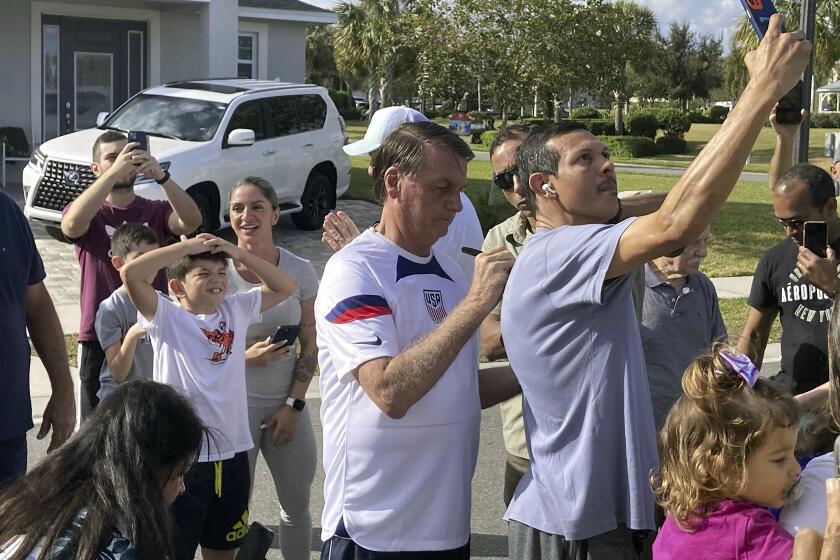 Former Brazil President Jair Bolsonaro, center, meets with supporters outside a vacation home where he is staying near Orlando, Fla., on Wednesday, Jan. 4, 2023. (Skyler Swisher/Orlando Sentinel via AP)