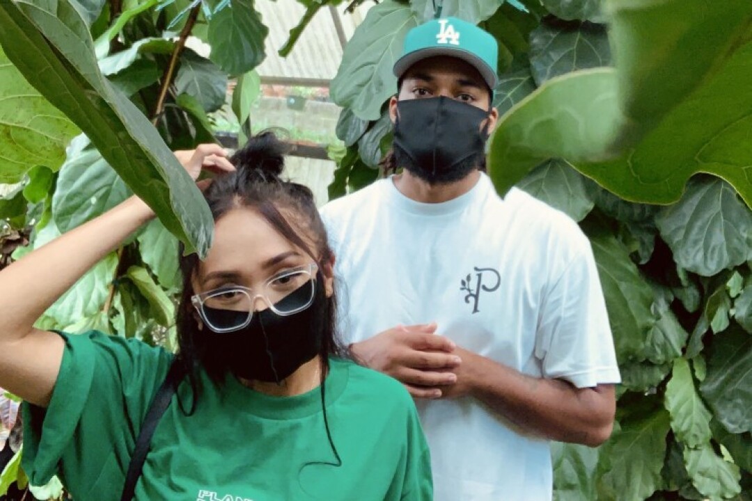 A masked woman and man surrounded by plants