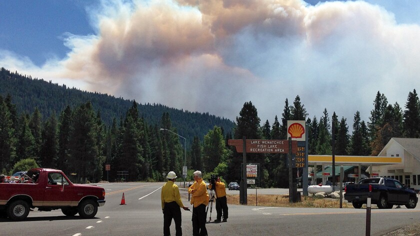 Plumes of smoke from the Leavenworth wildfire, as seen from Highway 2 in Washington, arc in the sky.