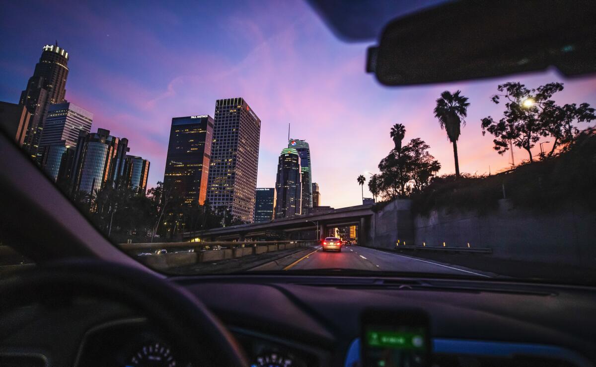 A car driving through downtown Los Angeles at sunset. 