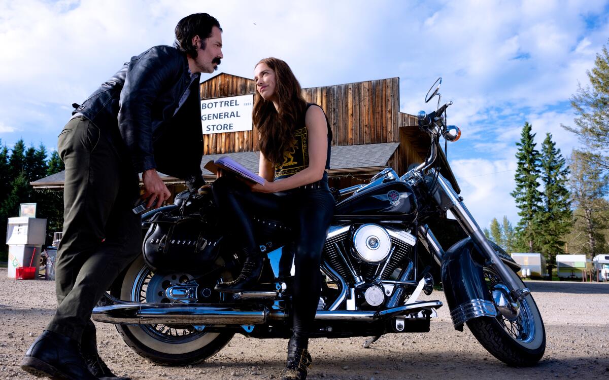 A man and woman leaning on a motorcycle