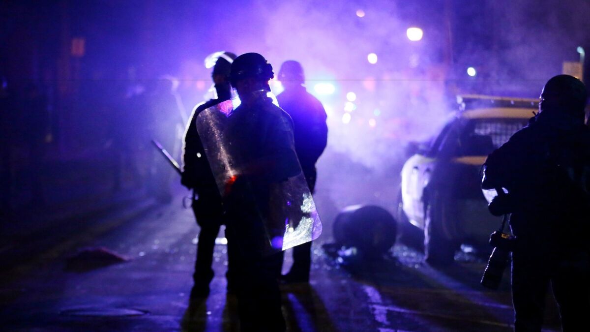 On Nov. 25, 2014, police officers watch protesters as smoke fills the streets in Ferguson, Mo.
