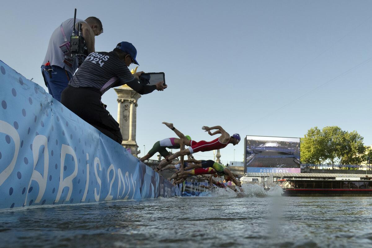 Athletes jump into the Seine River during the mixed-relay triathlon on Monday.