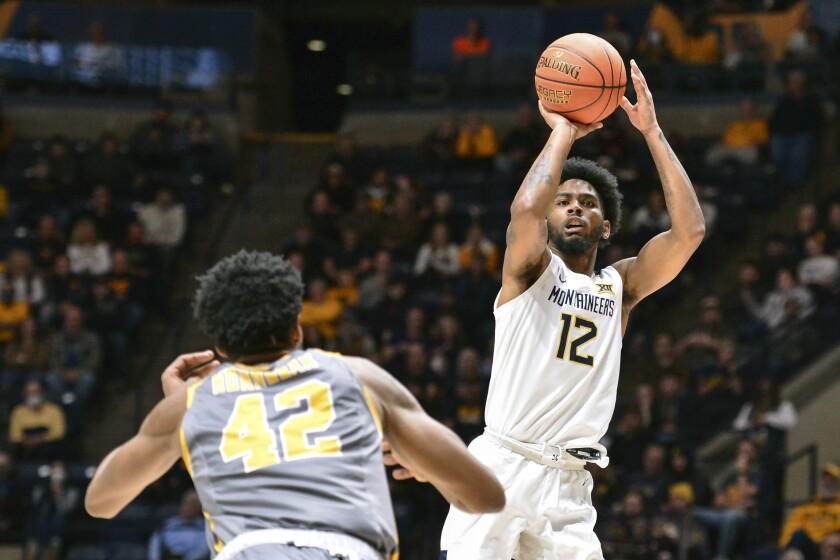 West Virginia forward Isaiah Cottrell (13) makes a three point basket while being guarded by Kent State center Cli'Ron Hornbeak (42) during the first half of an NCAA college basketball game in Morgantown, W.Va., Sunday, Dec. 12, 2021. (AP Photo/William Wotring)