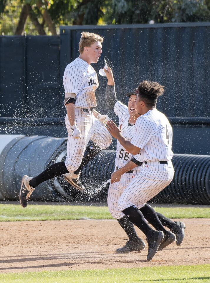 Huntington Beach High's Jag Burden, left, celebrates with teammates Ken Takada (56), and Edward Pelc (4) after his walk-off hit against Bishop Amat in the second round of the CIF Southern Section Division 1 playoffs on Tuesday.