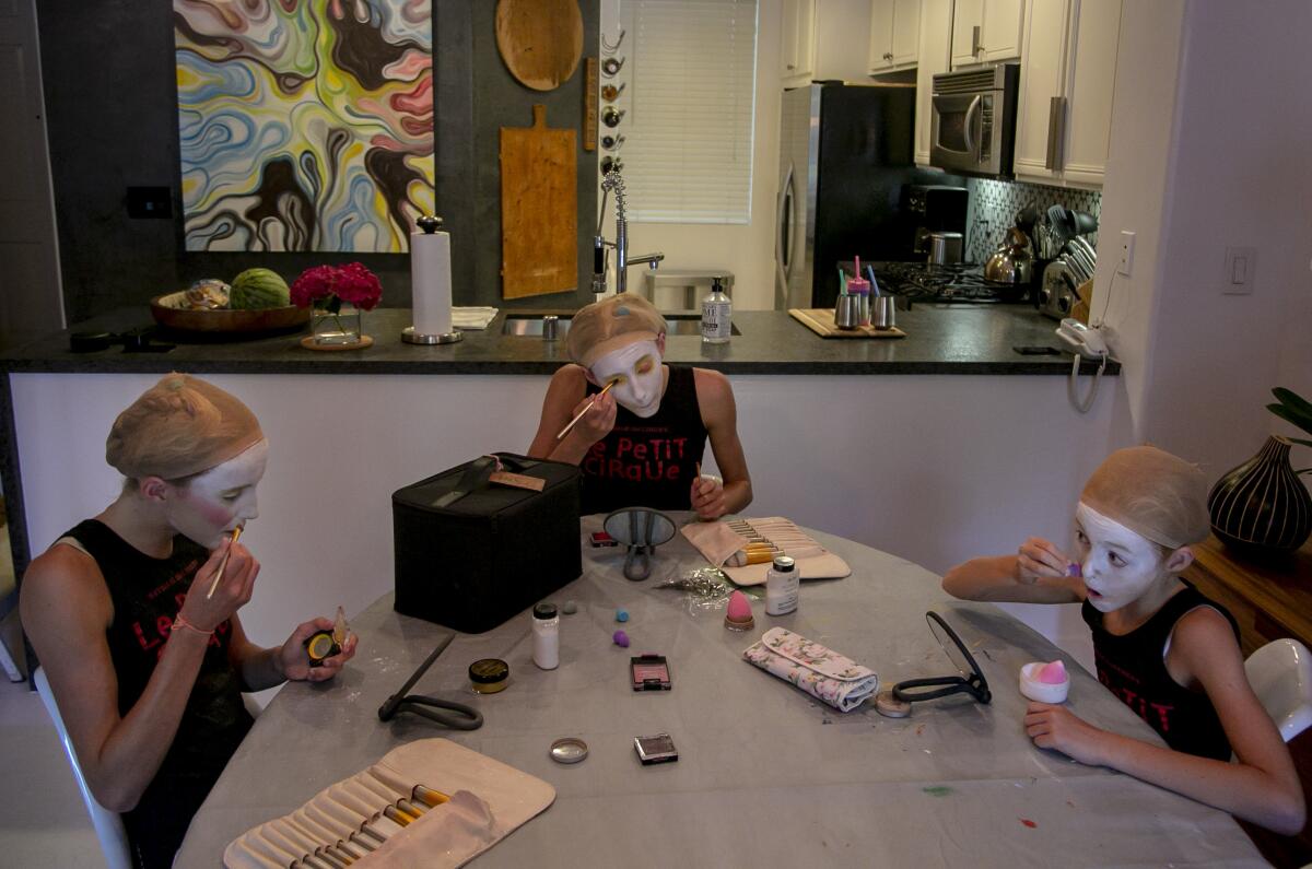 From left, sisters Brooklyn, 15, Brinkley, 15, and Bixby, 11, apply circus makeup at home in Playa Vista, Aug. 27, 2020 