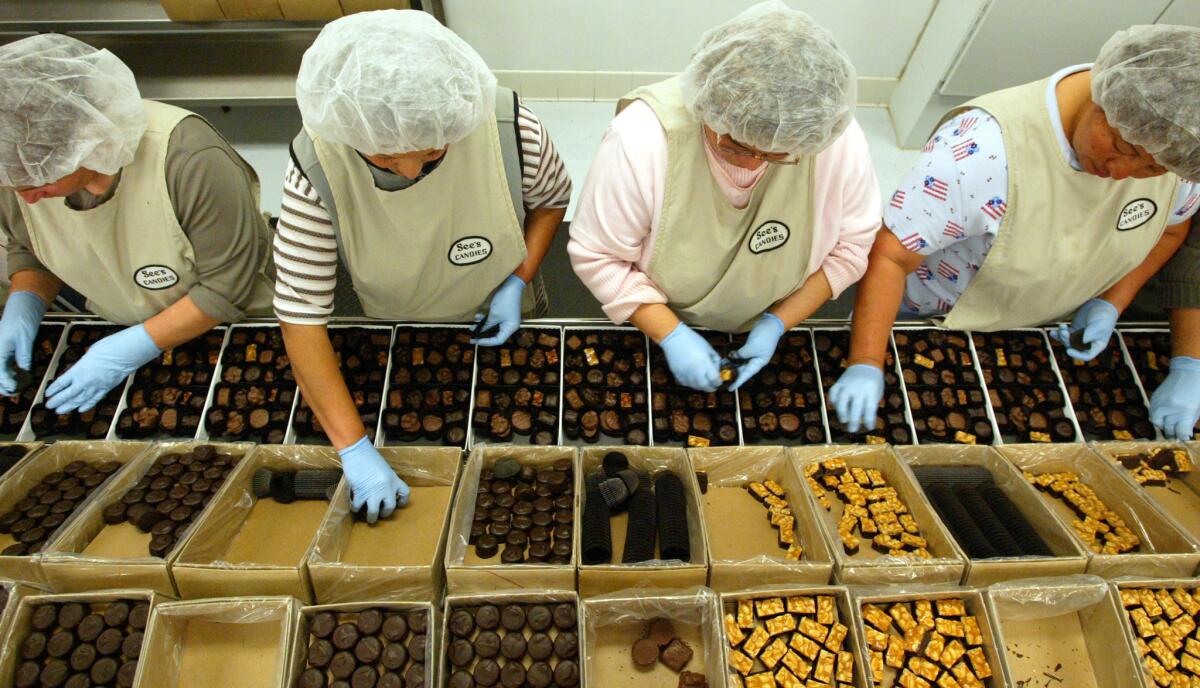 Workers pack boxes of See's chocolate at the company's Carson plant.