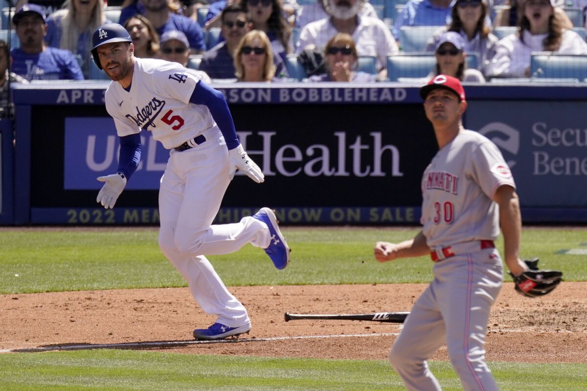 Dodgers batter Freddie Freeman, left, runs to first after hitting off Cincinnati Reds starting pitcher Tyler Mahle.