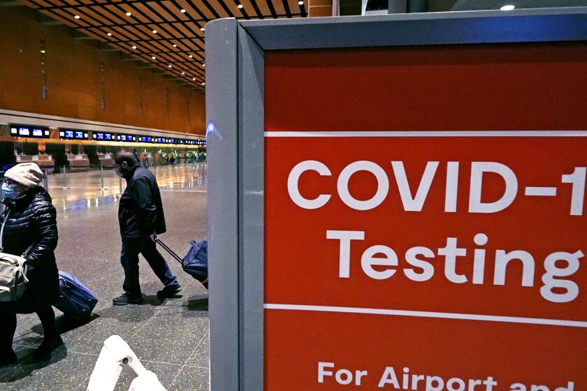 ARCHIVO - Viajeros pasan junto a un letrero cerca de un centro de pruebas de COVID-19 en la Terminal E del aeropuerto Logan el 21 de diciembre de 2021, en Boston.(AP Foto/Charles Krupa, Archivo)
