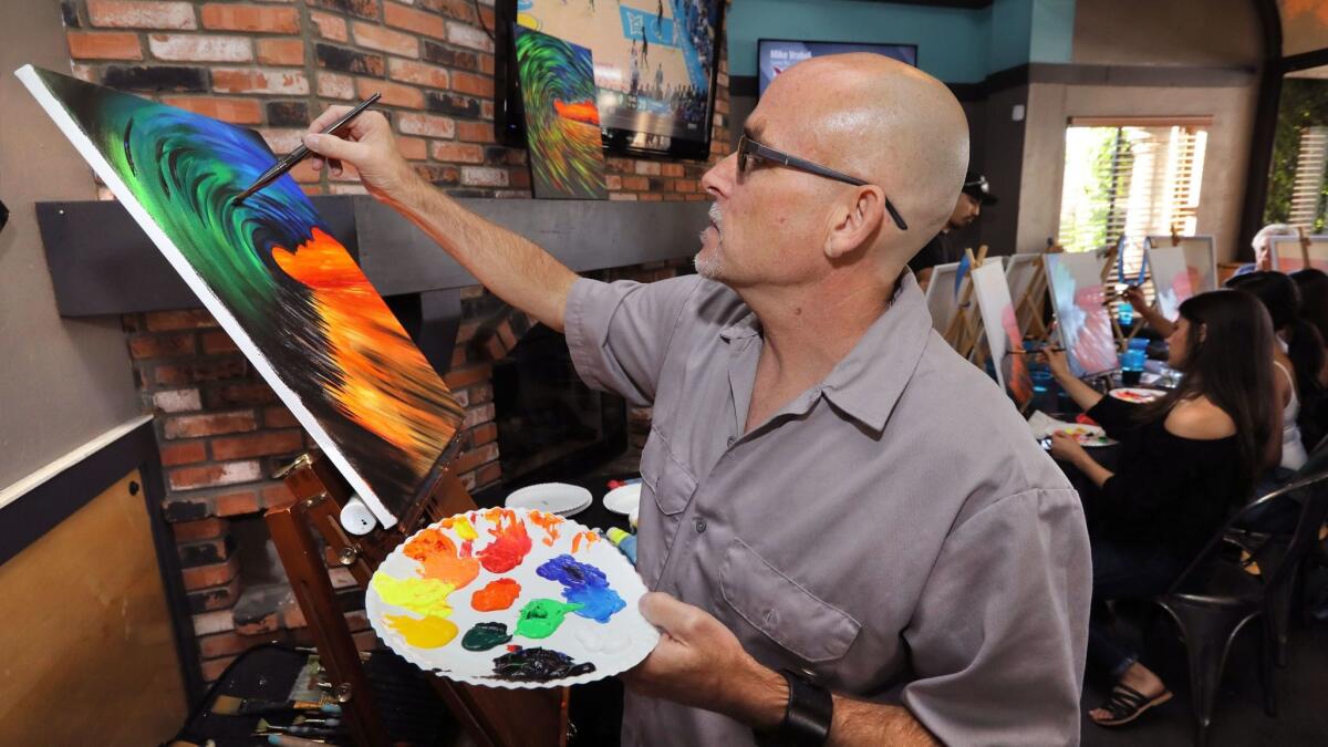Artist Al Scholl works on his painting of a colorful wave as he teaches his Art Therapy class at the Inland Tavern in San Marcos on Jan. 20.