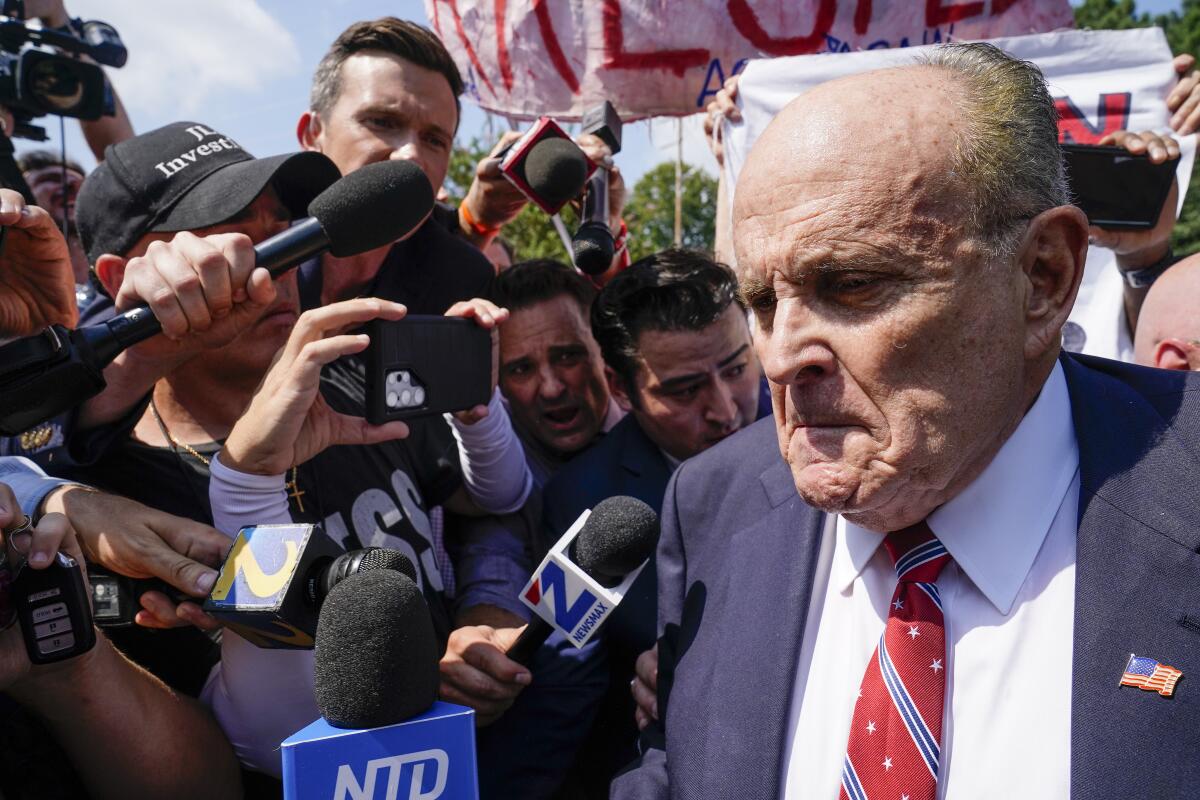 Rudolph Giuliani surrounded by reporters with microphones