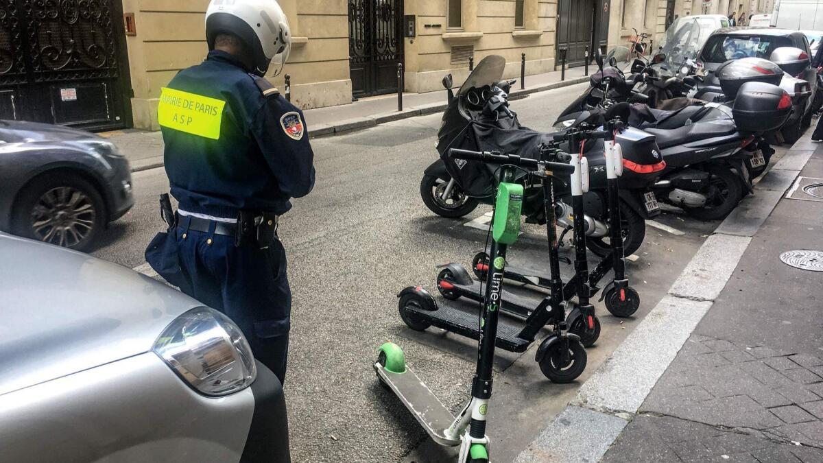 An official from the mayor of Paris' office moves electric scooters from car parking spaces into those for motorcycles on a road in the French capital on June 6, 2019.